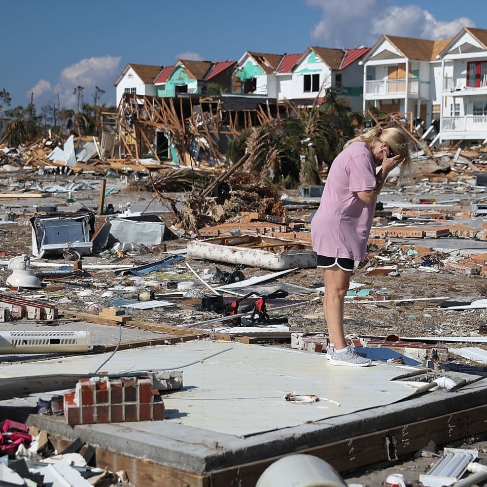 woman standing in hurricane wreckage